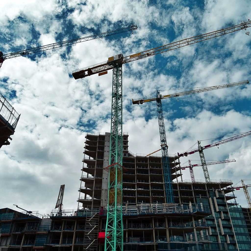 pexels photo 439416 439416 Urban construction site with numerous cranes framing rising skyscrapers against a blue sky.